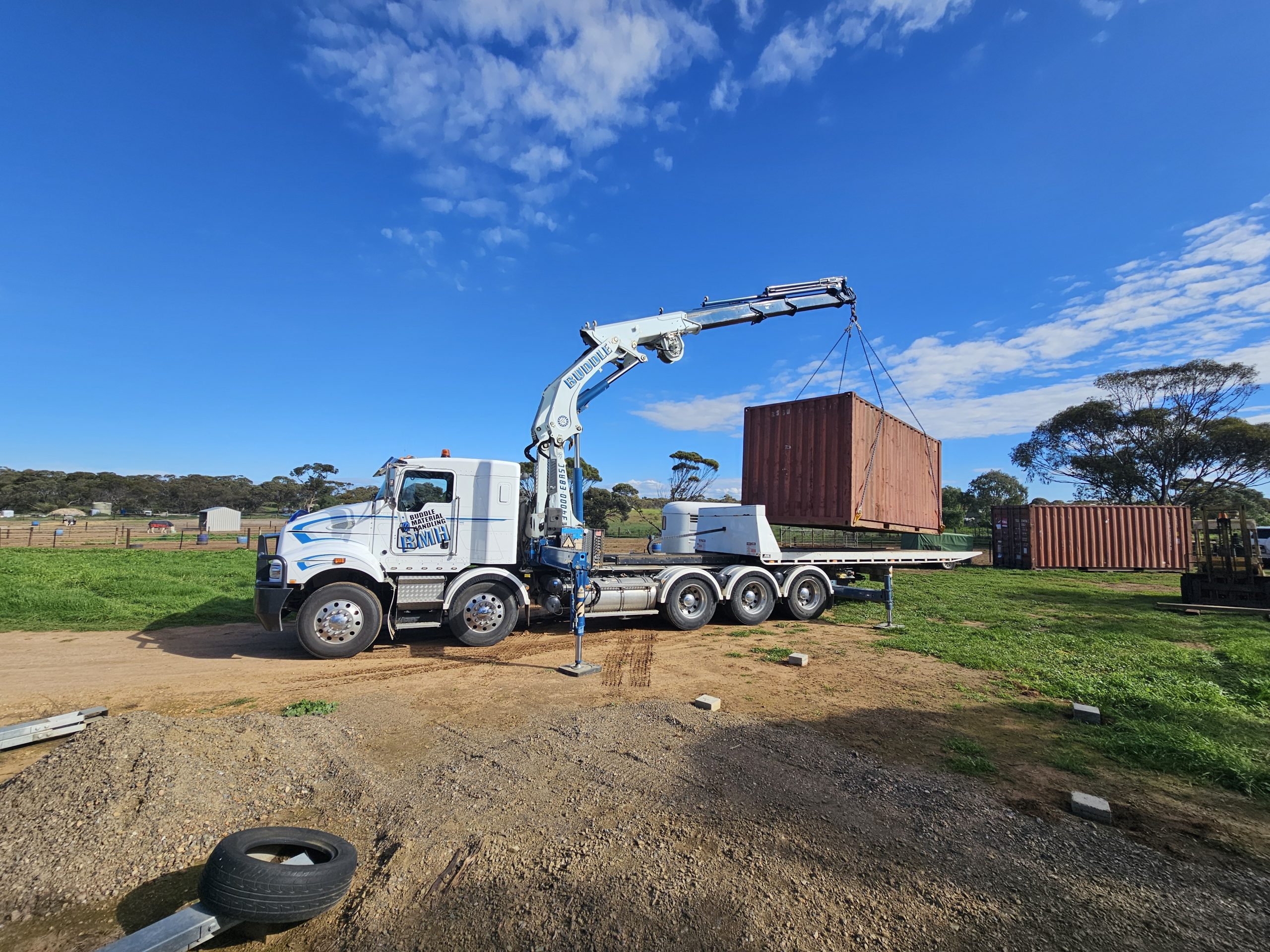 Tilt tray crane truck delivering a 20ft container
